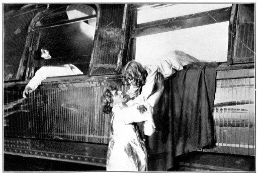 A man pulls a woman through the window of a railcar.