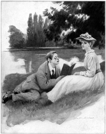 A man and a woman sit on the ground by the water.