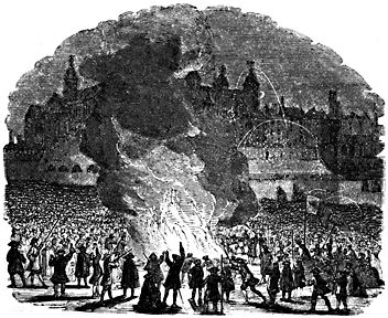 A huge crowd surrounds a roaring fire.