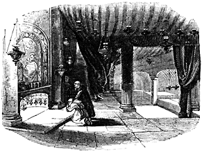 A man kneels at a low altar in a heavily draped room.