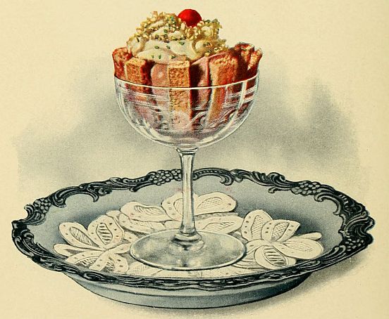 goblet filled with trifle topped iwth cream and cherry